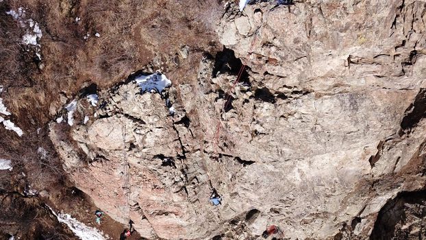 A group of people are engaged in rock climbing. High steep cliff. With the help of a rope, insurance and a partner, climbers climb to the top. Winter time of the year, sometimes there is snow.