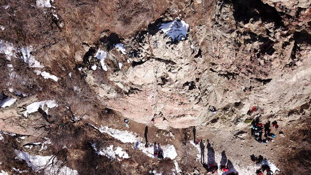 A group of people are engaged in rock climbing. High steep cliff. With the help of a rope, insurance and a partner, climbers climb to the top. Winter time of the year, sometimes there is snow.