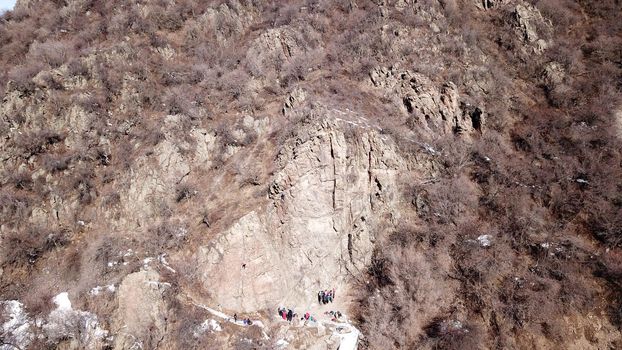 A group of people are engaged in rock climbing. High steep cliff. With the help of a rope, insurance and a partner, climbers climb to the top. Winter time of the year, sometimes there is snow.