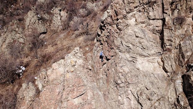 A group of people are engaged in rock climbing. High steep cliff. With the help of a rope, insurance and a partner, climbers climb to the top. Winter time of the year, sometimes there is snow.