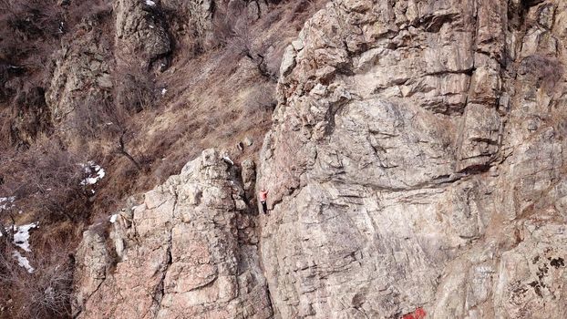 A group of people are engaged in rock climbing. High steep cliff. With the help of a rope, insurance and a partner, climbers climb to the top. Winter time of the year, sometimes there is snow.