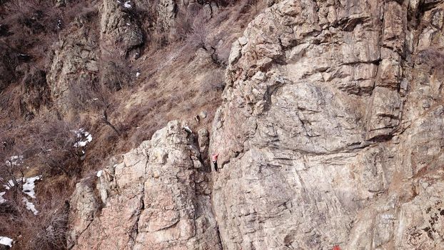 A group of people are engaged in rock climbing. High steep cliff. With the help of a rope, insurance and a partner, climbers climb to the top. Winter time of the year, sometimes there is snow.