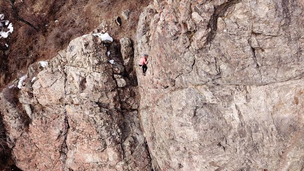 A group of people are engaged in rock climbing. High steep cliff. With the help of a rope, insurance and a partner, climbers climb to the top. Winter time of the year, sometimes there is snow.