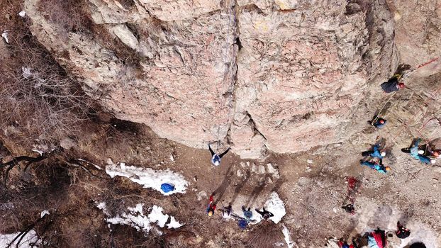 A group of people are engaged in rock climbing. High steep cliff. With the help of a rope, insurance and a partner, climbers climb to the top. Winter time of the year, sometimes there is snow.