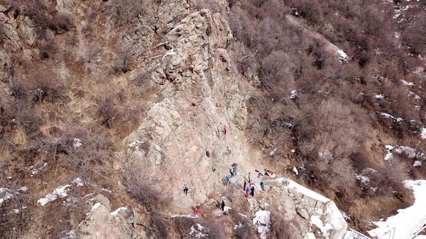 A group of people are engaged in rock climbing. High steep cliff. With the help of a rope, insurance and a partner, climbers climb to the top. Winter time of the year, sometimes there is snow.