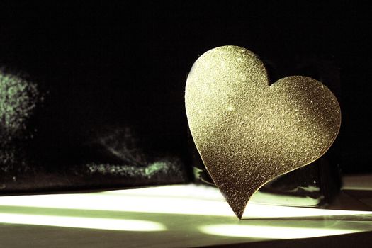 Golden shiny heart on black background