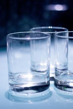 Three empty crystal glasses on dark background. No people