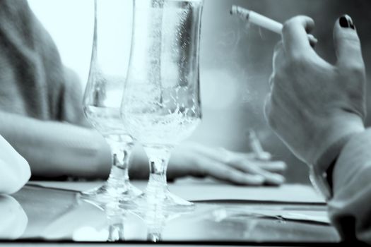 Hands holding a cigarette with empty beer glasses. Copy space