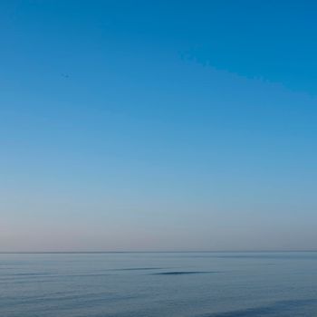 very calm blue sea water with one small wave under blue sky