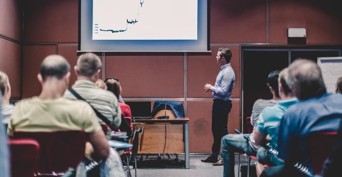 Speaker giving a talk in conference hall at business event. Unrecognizable people in audience at conference hall. Business and Entrepreneurship concept.