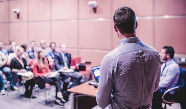 Speaker giving a talk on corporate business conference. Unrecognizable people in audience at conference hall. Business and Entrepreneurship event.