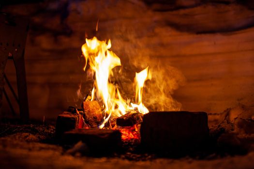 A campfire burns in the snow at night in the snow in the cold winter. The flame of the fire warms and illuminates. Flame, background