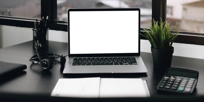 Mockup blank screen laptop and office supplies on white desk..