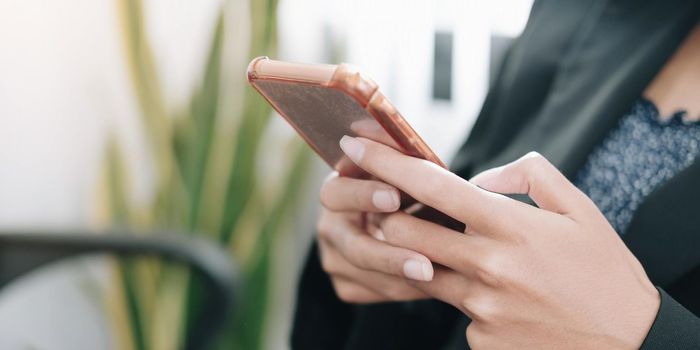 Close up woman use of smart phone on workplace at office.