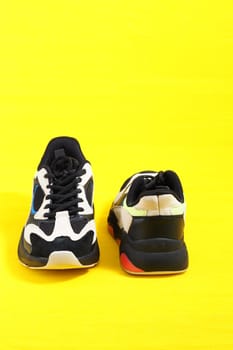 Sports shoes. Stylish fashionable sneakers on a yellow background. Vertical image. High quality photo