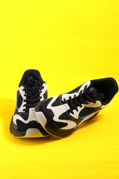 Sports shoes. Stylish fashionable sneakers on a yellow background. Vertical image. High quality photo