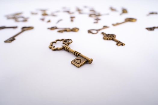 Close up of a vintage key with a heart engraving and collection of other scattered keys in the background. Love symbol. Valentine’s day, love, marriage concept. Key to my heart concept. Selective focus.