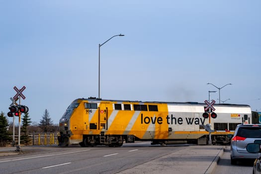 Ottawa, Ontario, Canada - March 25, 2021: A Via Rail train crosses Woodroofe Avenue as it departs Fallowfield Station north of Barrhaven.