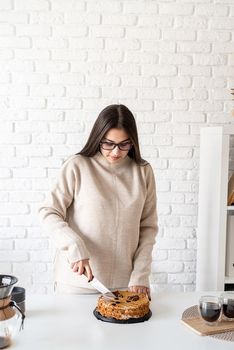 Alternative coffee brewing. Young woman brewing coffee in coffee pot and cutting a cake