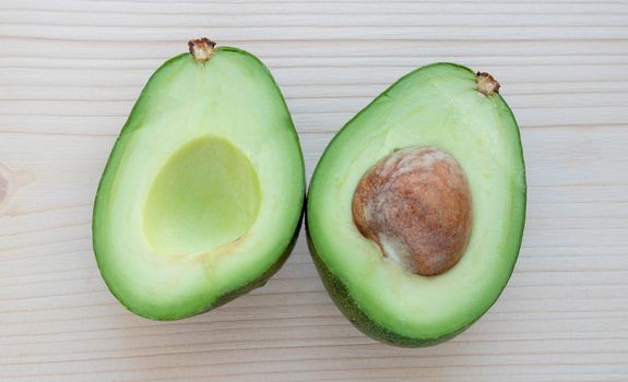 Slices of ripe avocado lie on a light cutting board.