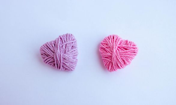 Two thread hearts hang on a white background. Holiday card, background. The concept of Valentine's Day, March 8, Mother's Day.
