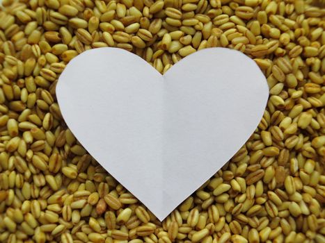 White Heart shape on Heap of raw wheat background