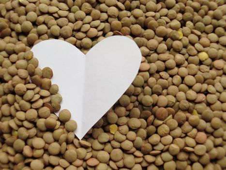 White Heart shape on Heap of raw lentils background