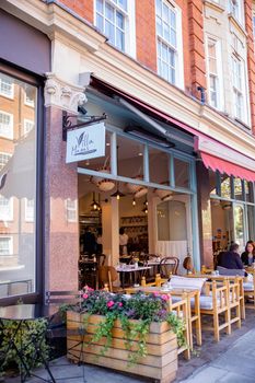 London, UK - February 14, 2020: Front side of restaurant Villa Mamas from Chelsea in London. Bahraini restaurant with man and woman sitting outside. Great London restaurants
