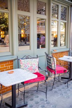 Comfy metal chairs and tables outside restaurant from Chelsea in London. Restaurant tables and chairs next to windows and door. Great London restaurants