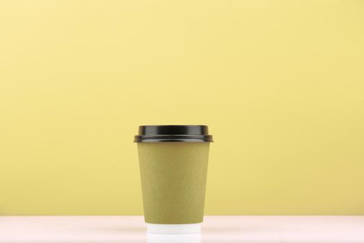 Disposable tea or coffee cup for hot drinks on white table against light green background with copy space. Concept of take away drinks