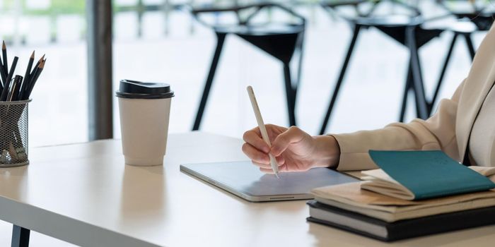 Close uo businesswoman holds pen stylus drawing on digital tablet on workplace.