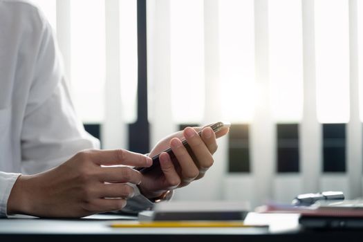 close up hand of businessman using mobile phone at office building, online business concept