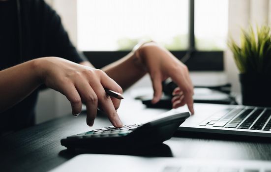 Close up hands businessman doing finances with using calculator and laptop computer in office.