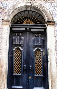 Old wooden door in Lisbon. Wrought metal details on the door.