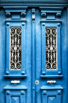 Old wooden door with tiled facade in Lisbon. Wrought metal details on the door.