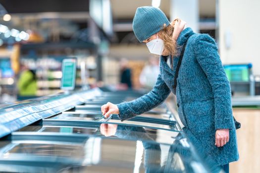 woman in the store chooses food from the freezer.