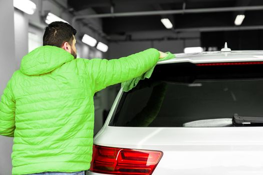 man cleans the car body with a towel. auto care.