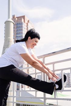 Sport and fitness. Senior sport. Active seniors. Smiling senior woman doing stretching outdoors on urban background