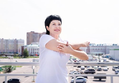 Sport and fitness. Senior sport. Active seniors. Smiling senior woman doing stretching outdoors on urban background