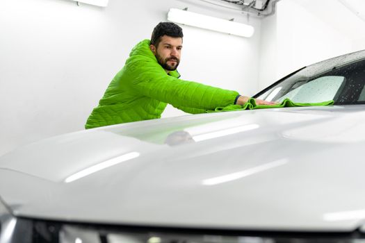 man cleans the car body with a towel. auto care.