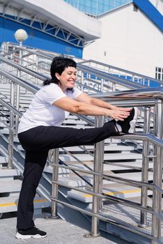 Sport and fitness. Senior sport. Active seniors. Smiling senior woman doing stretching outdoors on urban background