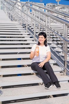 Sport and fitness. Senior sport. Active seniors. Smiling senior woman drinking water after workout outdoors on urban background