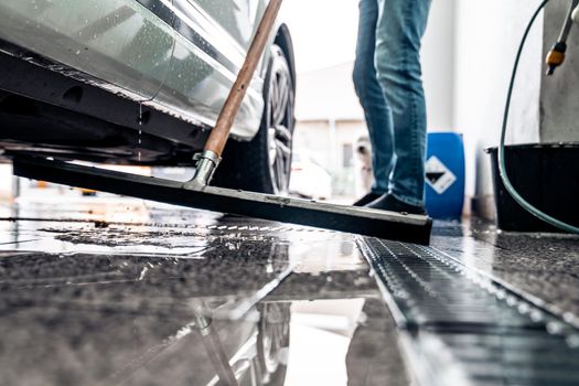 Clean the floor at the car wash with the help of a water spatula.