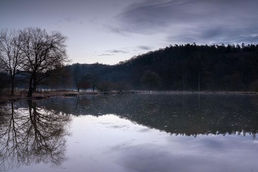 Fishpond close to Lindlar with water reflection during early morning mood, Bergisches Land, Germany