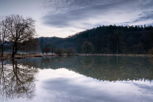 Fishpond close to Lindlar with water reflection during early morning mood, Bergisches Land, Germany