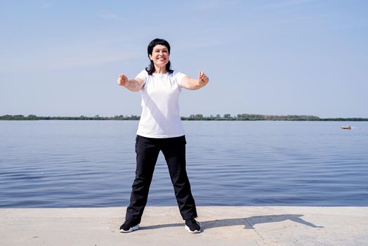 Sport and fitness. Senior sport. Active seniors. Active and happy senior woman exercising near the riverside