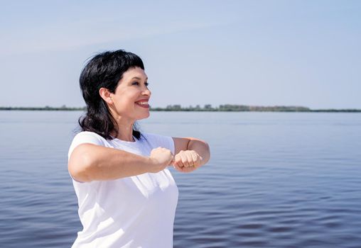 Sport and fitness. Senior sport. Active seniors. Active and happy senior woman exercising near the riverside