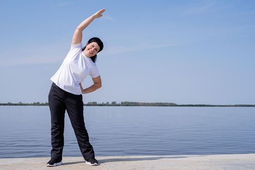 Sport and fitness. Senior sport. Active seniors. Active and happy senior woman doing stretching near the riverside