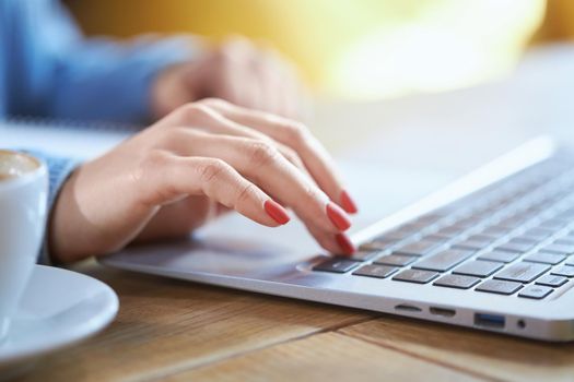 Close up of business woman hand typing on laptop keyboard. Concept of process working and preparing interesting information in laptop with tasty coffee on table. 