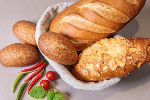 Fresh bread in a basket on the table with red peppers and tomatoes. Close-up